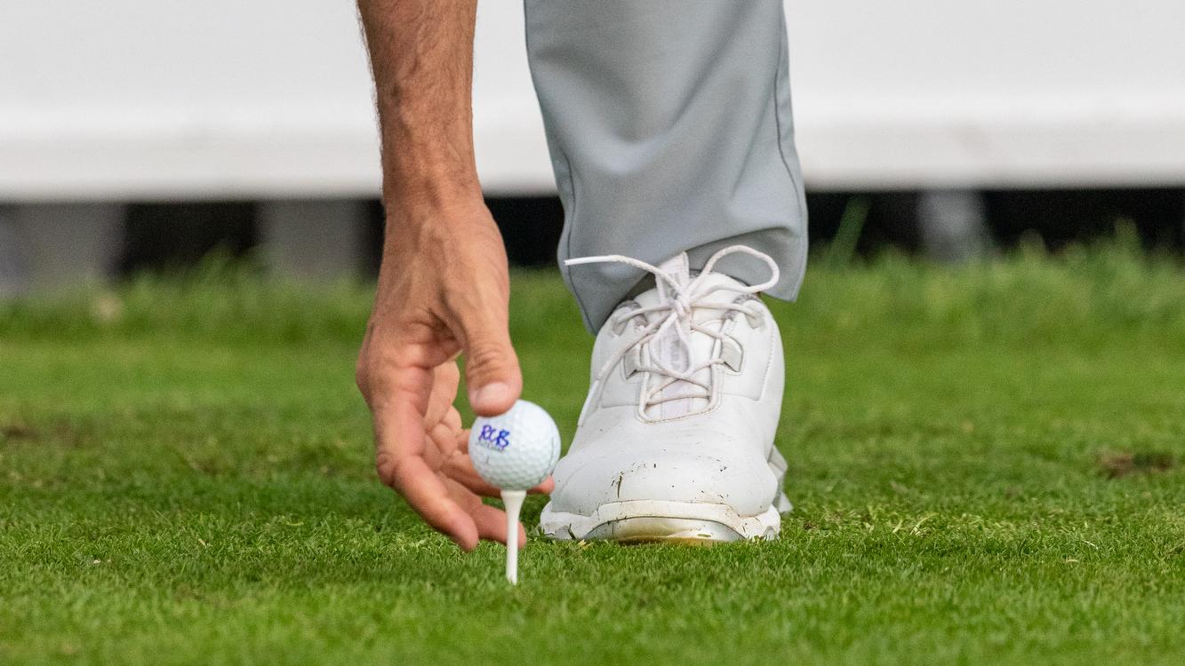 Un golfista coloca el tee.