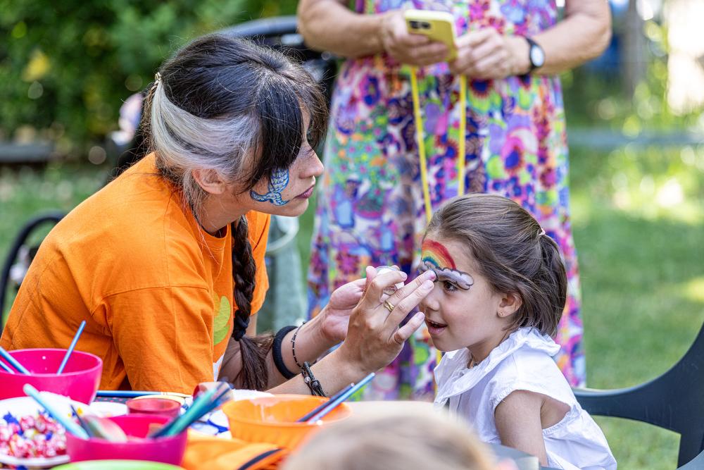 Una monitora decora la cara de una niña en la actividad del pintacaras.