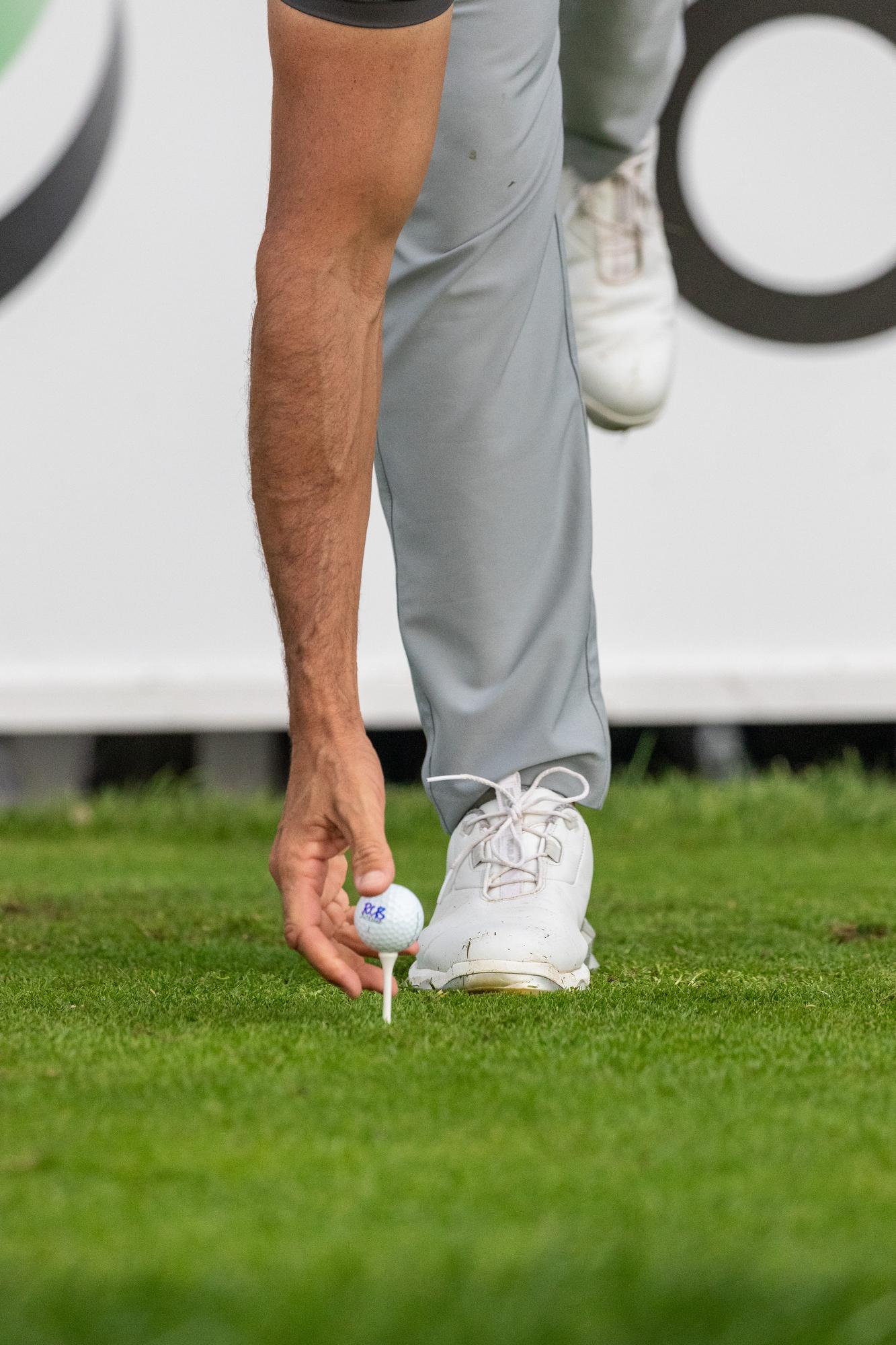 Un golfista coloca el tee.