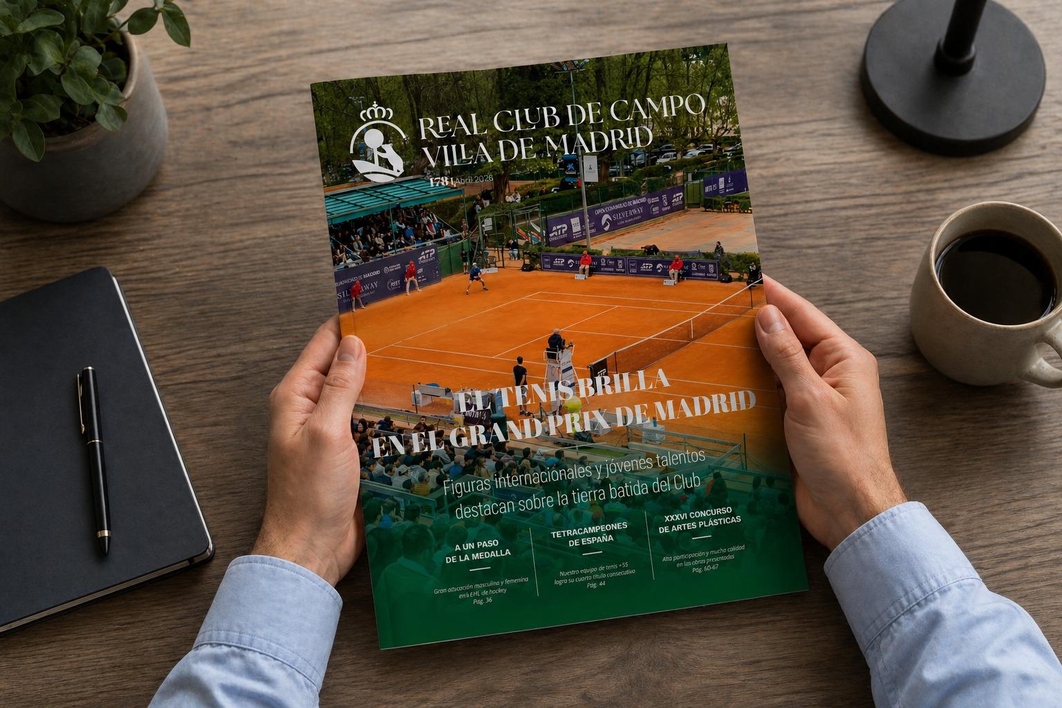 Dos manos sostienen la Revista RCCVM abril 2026, sobre una mesa con una libreta, un bolígrafo, una taza de café, una lámpara y una planta.