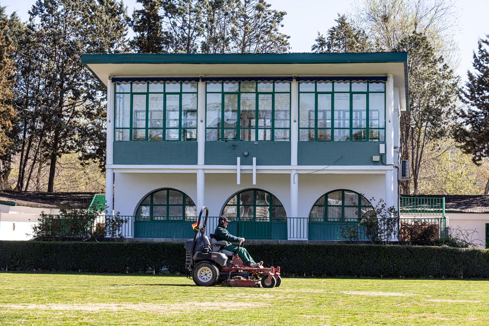 Un operario corta el césped de la Pista Verde.