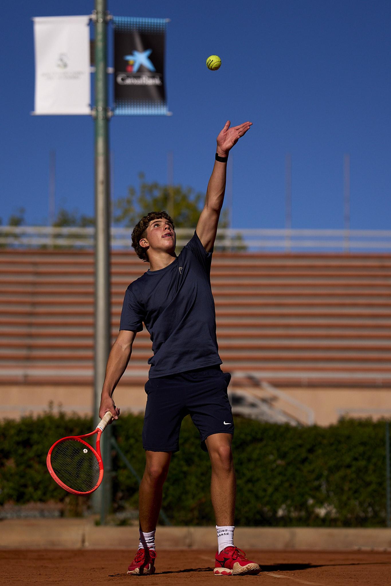 Un joven tenista lanza la pelota al aire para realizar un saque.